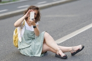 美女坐在马路上手机拍照图片