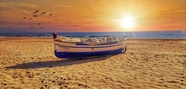 黄昏海滩木船夕阳图片