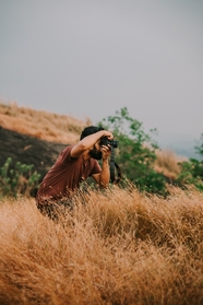 摄影师帅哥站在枯草丛拍照图片