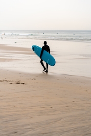 海边沙滩男人手持冲浪板图片