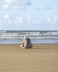 坐在海边沙滩的背包客图片