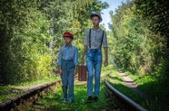 两个男孩提着行李走在铁轨上图片