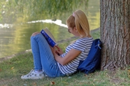 欧美美女坐在河边树下看书图片