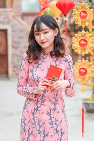 手持红包袋的越南粉色花卉奥黛美女图片
