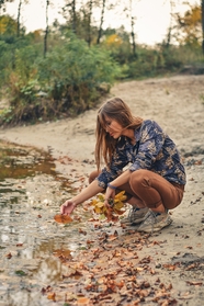 秋天美女站在溪边捡落叶图片