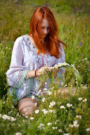 坐在花丛里编花环的欧美美女图片