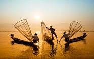 日暮黄昏海上渔民撒网捕鱼人物剪影图片
