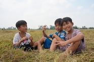 坐在田野稻草上的乡村孩童摄影图片