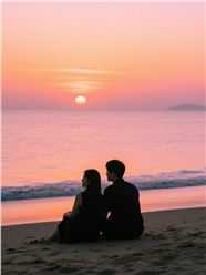 夕阳下坐在海边沙滩看海的情侣图片